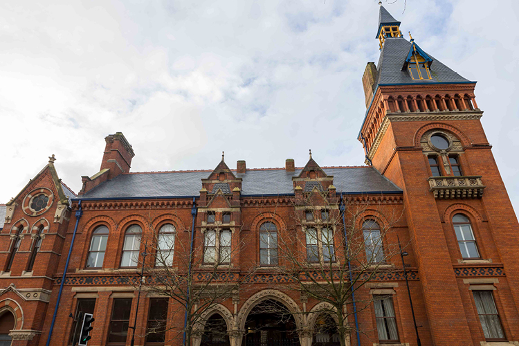 Ornate two storey red brick building with spire.