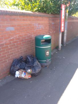 Rubbish placed on pavement next to rubbish bin