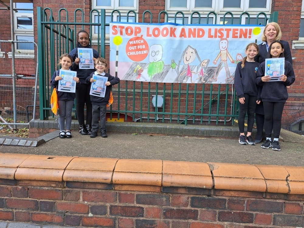 Head teacher and pupils of Rounds Green Primary School with their road safety sign